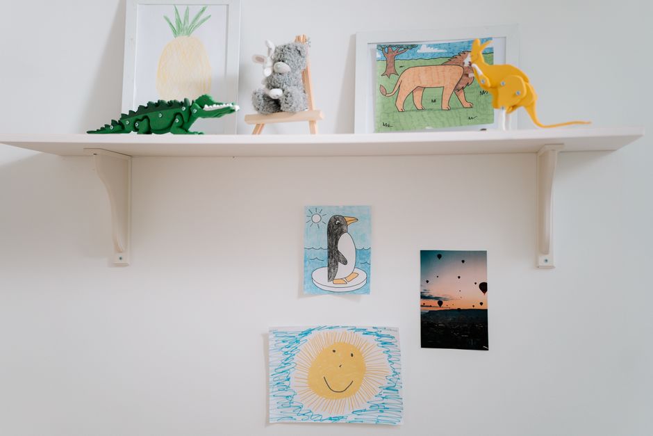 Otroške risbe v belih mat okvirjih v otroški sobi